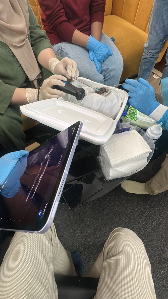 APPL participants gathered around a probe and tablet during a training session