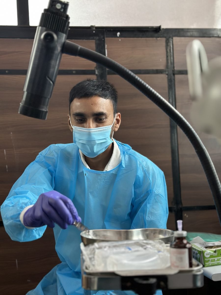Gowned participant preparing phantom material at the bench under a lamp
