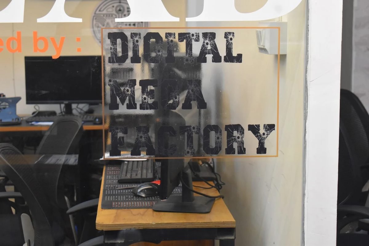 The Digital Mega Factory name on the studio glass, workstations behind
